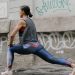 Woman doing lunges for fitness against an urban graffiti wall, showcasing exercise and wellness.